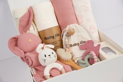 Blossom Breeze baby gift box with towel, blanket, teether, pacifier holder, rattle, nail care set, and milestone items in soft pink tones.